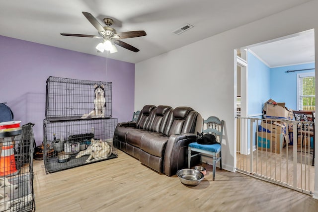 living room featuring hardwood / wood-style flooring, ceiling fan, and crown molding