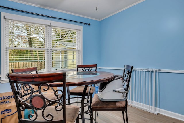 dining space featuring wood-type flooring, ornamental molding, and a wealth of natural light