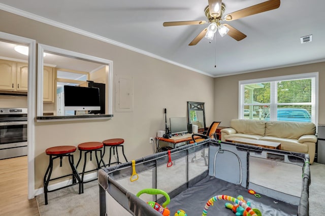 playroom with ceiling fan, light hardwood / wood-style floors, crown molding, and electric panel