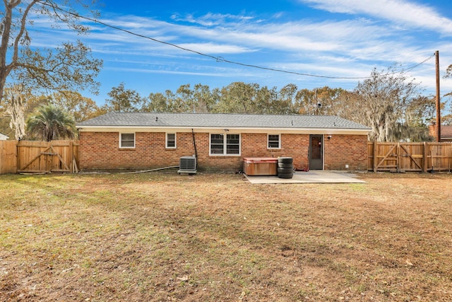 rear view of house with central air condition unit, a patio area, a yard, and a hot tub