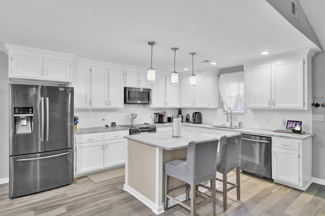 kitchen featuring hanging light fixtures, appliances with stainless steel finishes, sink, and white cabinets