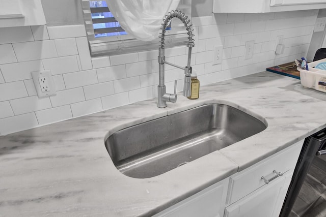 details featuring backsplash, black dishwasher, sink, and white cabinets