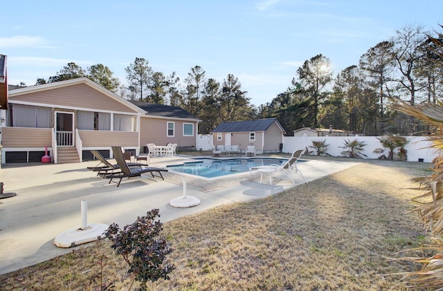 view of pool with a patio, a sunroom, and an outdoor structure