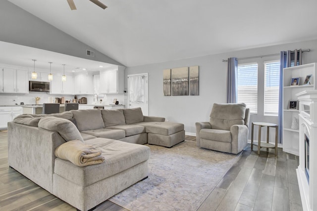 living room featuring ceiling fan, lofted ceiling, sink, and hardwood / wood-style floors