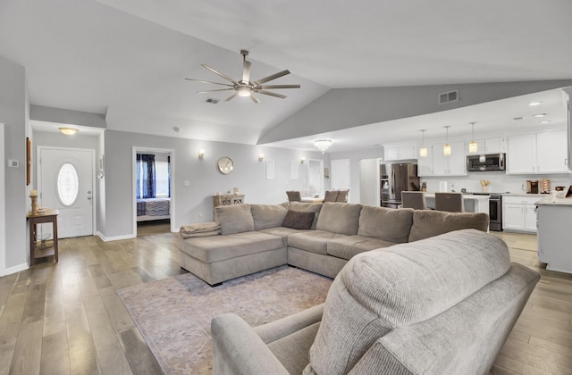 living room with vaulted ceiling, ceiling fan, and light wood-type flooring