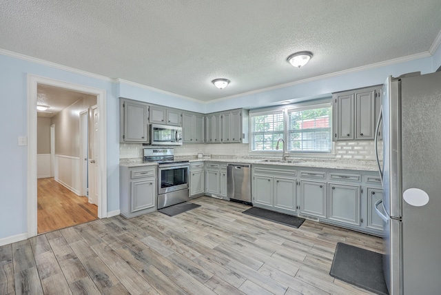 108 Reardon St, Moncks Corner, SC 29461 - kitchen featuring stainless steel appliances, light wood-style floors, a textured ceiling, gray cabinetry, and ornamental molding