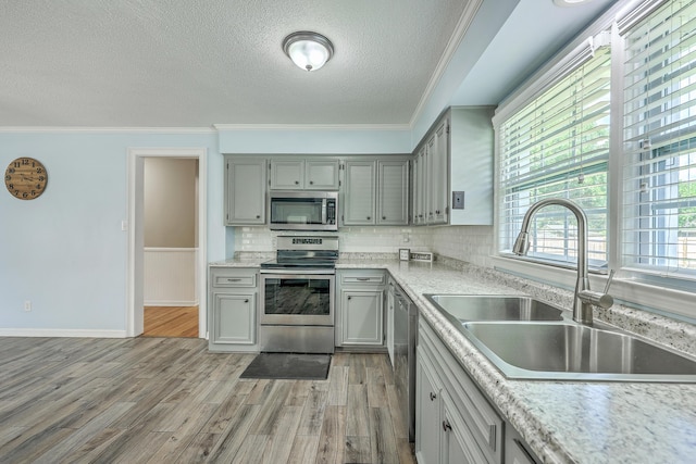 108 Reardon St, Moncks Corner, SC 29461 - kitchen featuring stainless steel appliances, gray cabinetry, a textured ceiling, crown molding, and light wood-style flooring