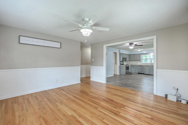 108 Reardon St, Moncks Corner, SC 29461 - unfurnished living room featuring light wood-type flooring, a ceiling fan, wainscoting, and a textured ceiling