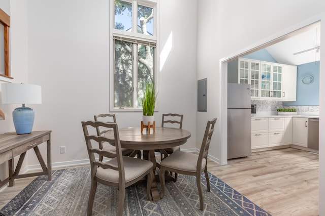 dining room featuring light hardwood / wood-style floors, electric panel, and high vaulted ceiling