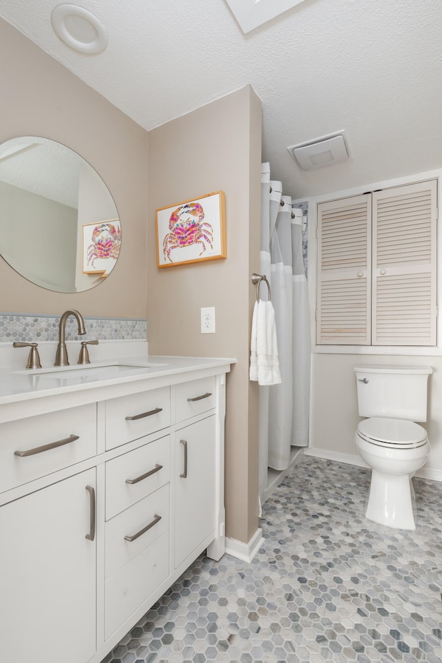 bathroom with a textured ceiling, vanity, and toilet