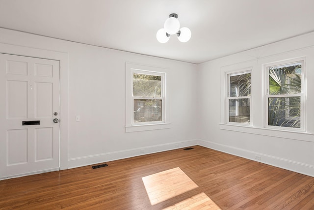 empty room featuring a chandelier and wood-type flooring