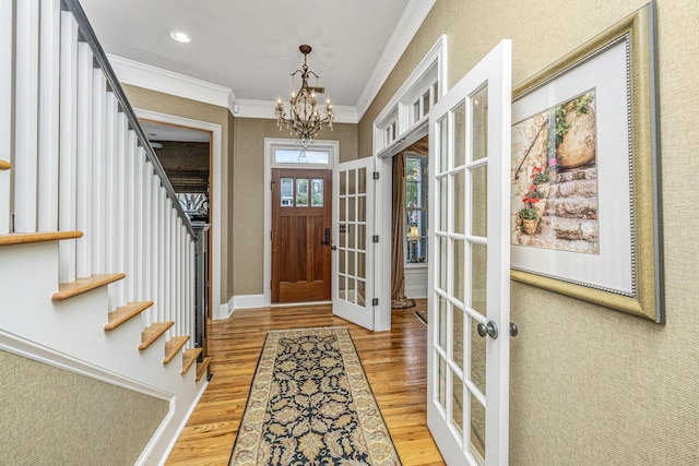 foyer entrance featuring a chandelier, hardwood / wood-style floors, french doors, and crown molding