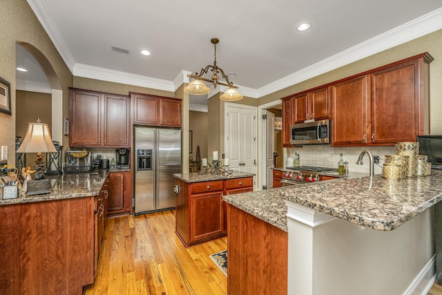 kitchen featuring pendant lighting, light wood-type flooring, appliances with stainless steel finishes, light stone counters, and kitchen peninsula