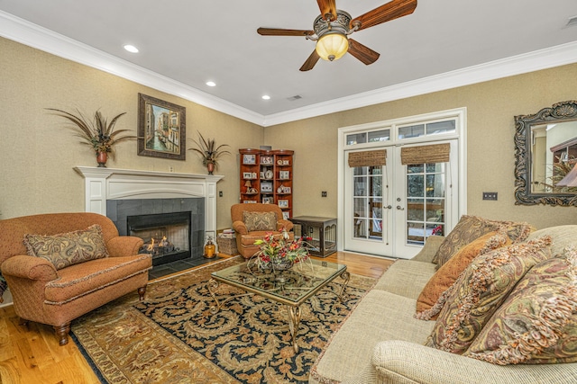 living room featuring hardwood / wood-style flooring, ornamental molding, a fireplace, and french doors