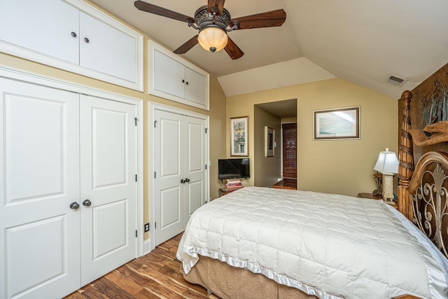 bedroom with wood-type flooring, vaulted ceiling, ceiling fan, and multiple closets