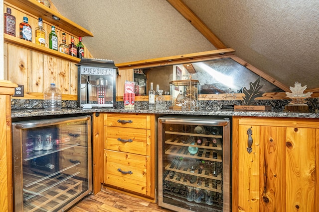 bar featuring a textured ceiling, light hardwood / wood-style flooring, wine cooler, and vaulted ceiling