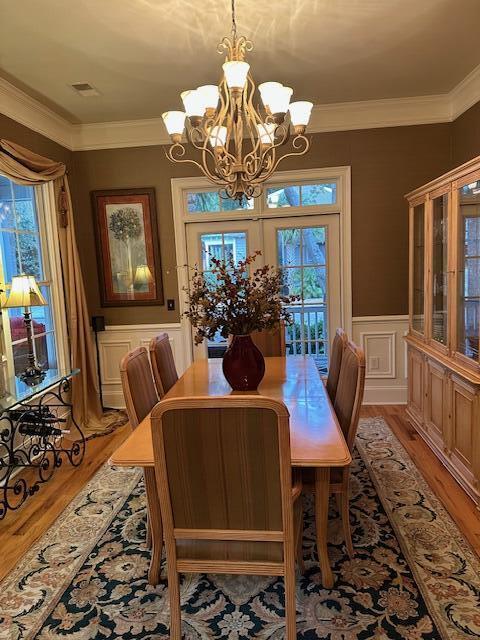 dining room with ornamental molding, light wood-type flooring, and a healthy amount of sunlight