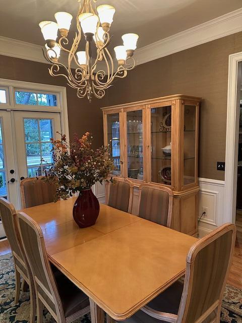 dining area with a notable chandelier, wood-type flooring, crown molding, and french doors