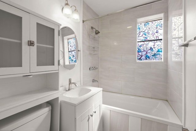 full bathroom featuring tiled shower / bath combo, vanity, a healthy amount of sunlight, and toilet