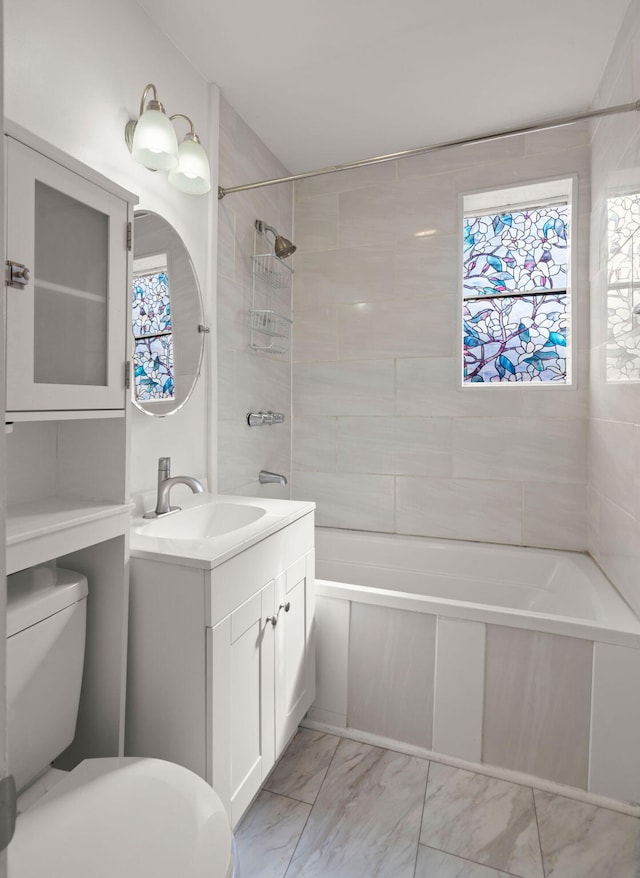 full bathroom with tiled shower / bath combo, vanity, and toilet