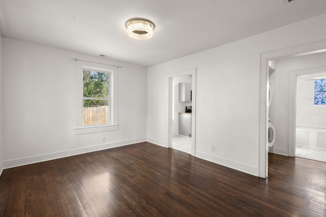 unfurnished bedroom featuring washer / clothes dryer, dark wood-type flooring, and ensuite bathroom