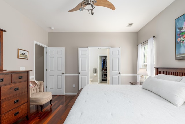 bedroom with visible vents, ensuite bathroom, dark wood-type flooring, a spacious closet, and a ceiling fan