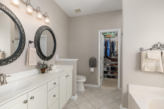 bathroom featuring a sink, tile patterned floors, baseboards, a spacious closet, and a bath