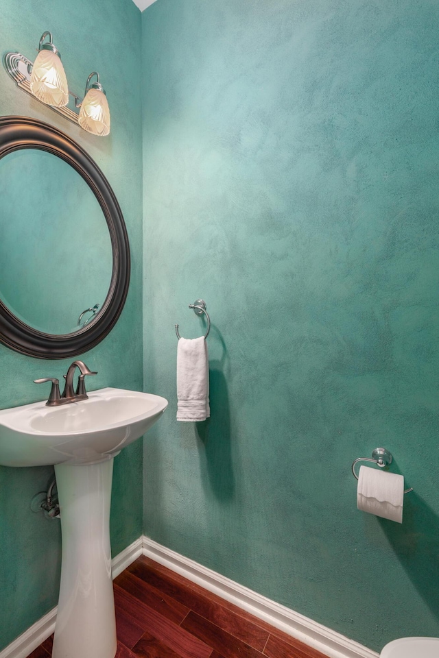 half bathroom with baseboards and wood finished floors