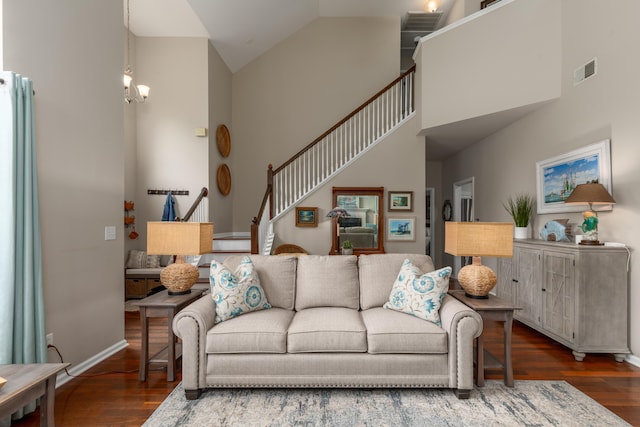 living area with an inviting chandelier, high vaulted ceiling, baseboards, wood finished floors, and visible vents