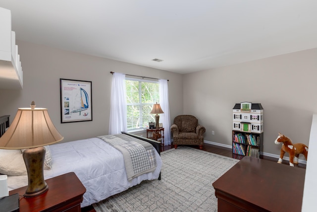 bedroom featuring baseboards, wood finished floors, and visible vents