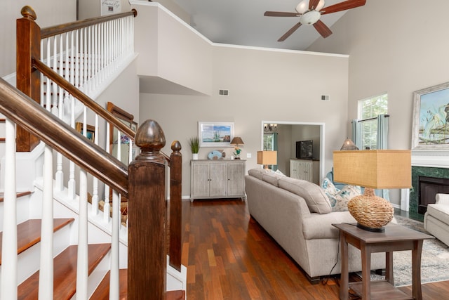 living area featuring dark wood finished floors, ceiling fan, and a high ceiling