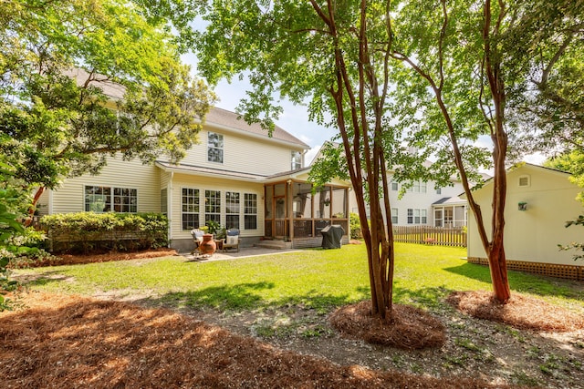 rear view of house with a lawn, fence, a patio, and a sunroom