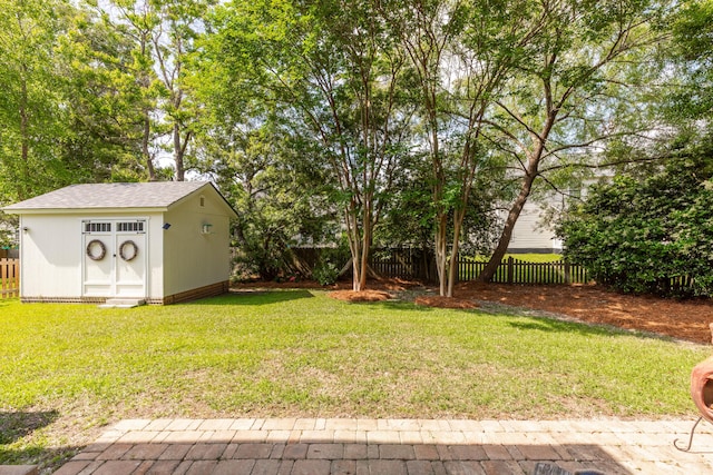 view of yard with a storage unit, a fenced backyard, and an outbuilding