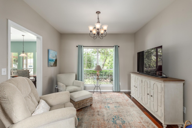 sitting room featuring dark wood-type flooring, baseboards, a notable chandelier, and a wealth of natural light