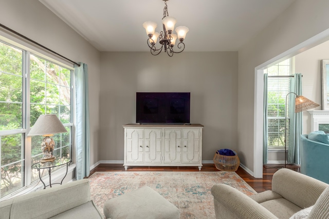 living area featuring an inviting chandelier, baseboards, and wood finished floors