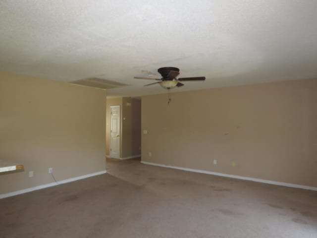 spare room with ceiling fan, light carpet, and baseboards