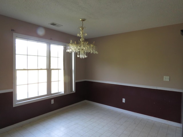 unfurnished dining area with a chandelier, a textured ceiling, and baseboards