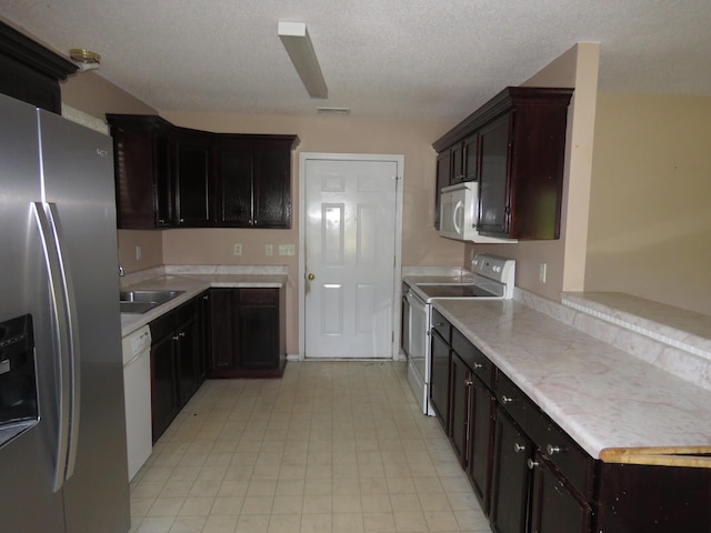 kitchen featuring white appliances, a sink, light countertops, light floors, and dark brown cabinets