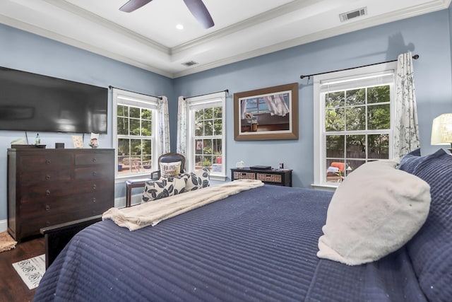bedroom featuring visible vents, ornamental molding, wood finished floors, and multiple windows