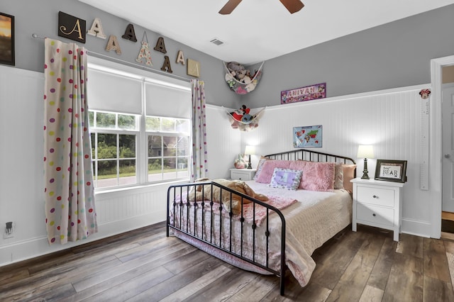 bedroom with a ceiling fan, visible vents, wainscoting, and hardwood / wood-style floors
