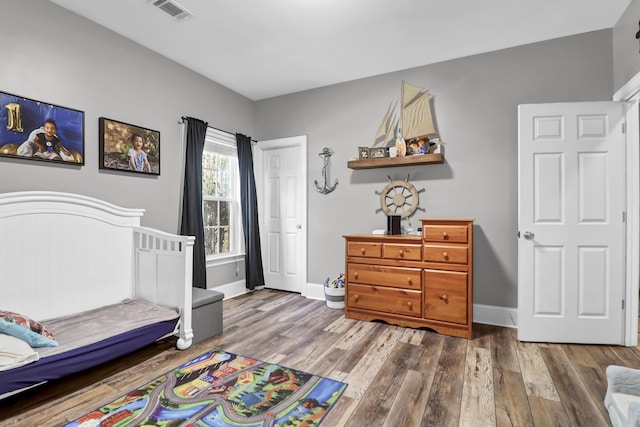 bedroom with baseboards, a closet, wood finished floors, and visible vents