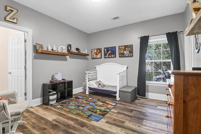bedroom with visible vents, baseboards, and wood finished floors