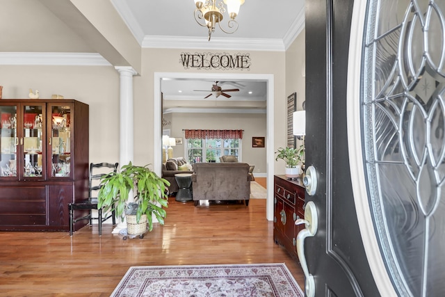 entryway featuring crown molding, a ceiling fan, decorative columns, and wood finished floors