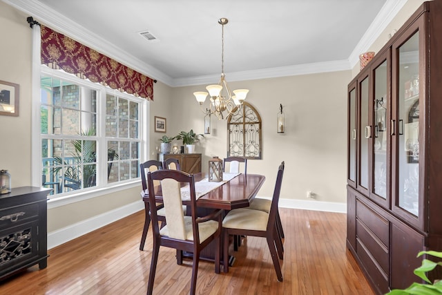 dining space with a chandelier, baseboards, visible vents, and light wood finished floors