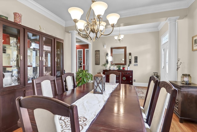 dining area featuring crown molding, ornate columns, an inviting chandelier, and light wood-type flooring