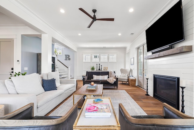 566 Wading Pl, Daniel Island, SC 29492 - living area featuring stairway, a glass covered fireplace, ceiling fan, wood finished floors, and crown molding