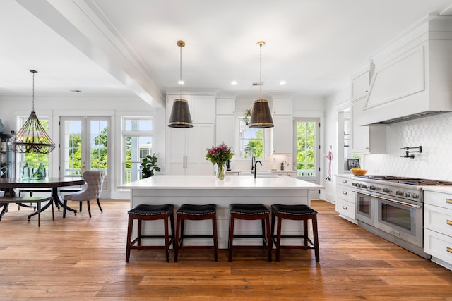 566 Wading Pl, Daniel Island, SC 29492 - kitchen featuring range with two ovens, light countertops, tasteful backsplash, a breakfast bar, and recessed lighting
