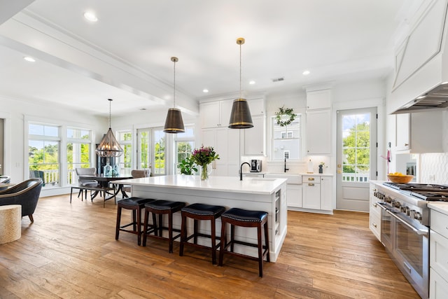 566 Wading Pl, Daniel Island, SC 29492 - kitchen with double oven range, custom range hood, light countertops, a breakfast bar area, and light wood-style floors