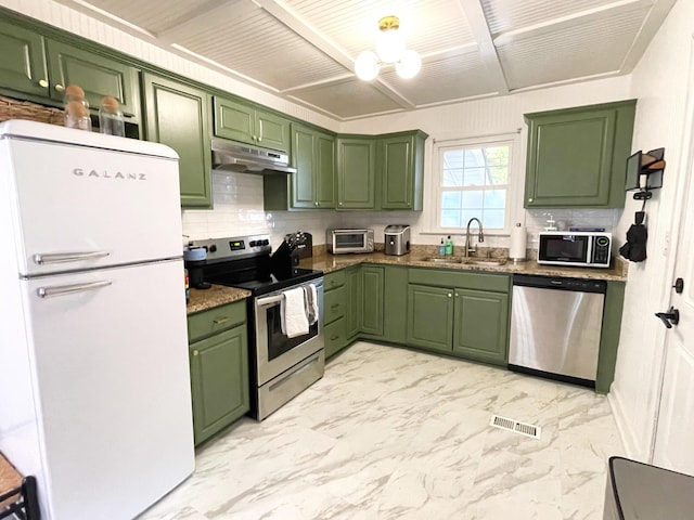 kitchen featuring decorative backsplash, a sink, green cabinets, under cabinet range hood, and stainless steel appliances