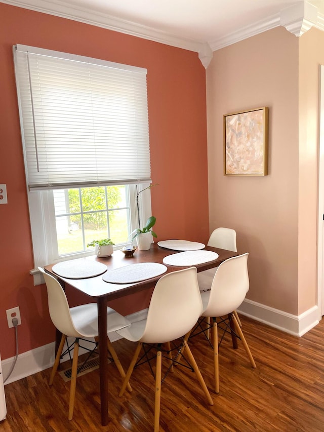 dining space with baseboards, ornamental molding, and wood finished floors
